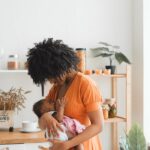 A loving mother gently holding her baby in a bright, cozy kitchen.