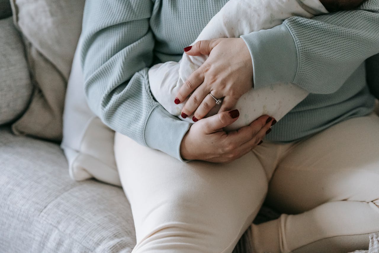 A serene moment of a mother embracing her newborn infant, symbolizing love and maternal care in a cozy living room setting.